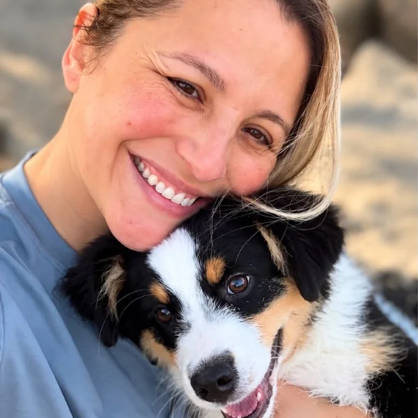 Gabriela abraçada ao Chico, seu filhote de mini pastor americano